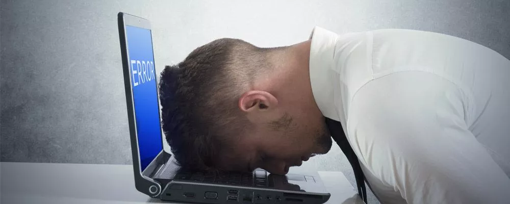Man banging head on a laptop