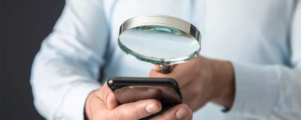 Man looking at a phone with magnifying glass