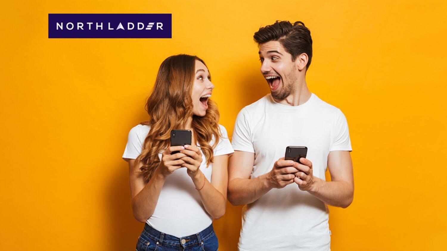Image of happy couple with phone in their hand looking at each other against a yellow background.